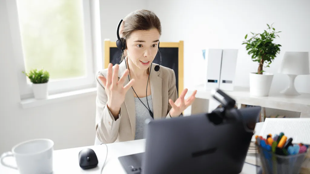 Young woman wearing headphones, seated behind a laptop, working as a customer support agent