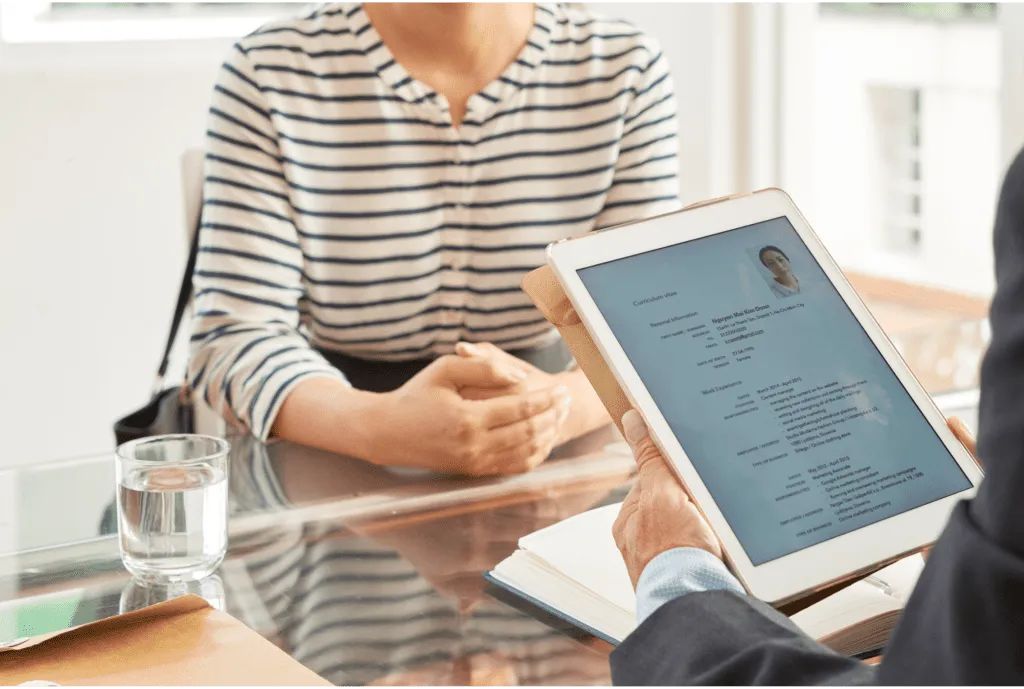 Close-up of a hiring manager holding a digital tablet displaying a candidate