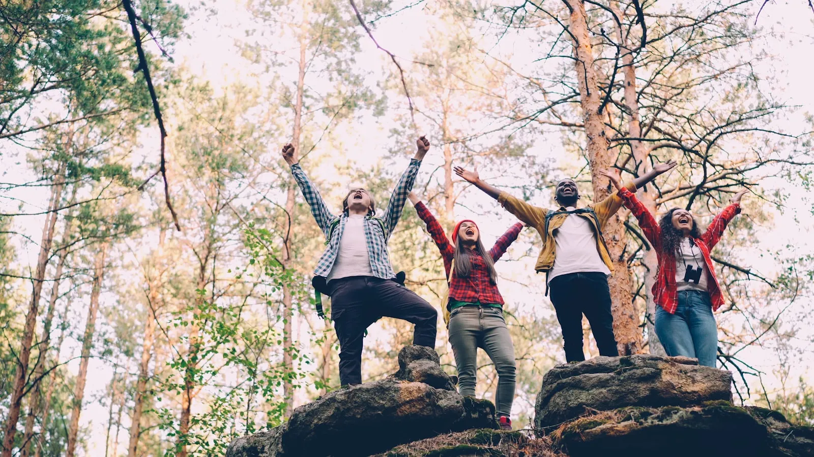 Four friends celebrating on rocky terrain outdoors