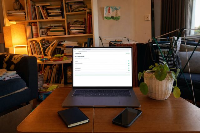 The Tasman Visa secure upload open on a laptop in a family living room, documents ticked off one by one