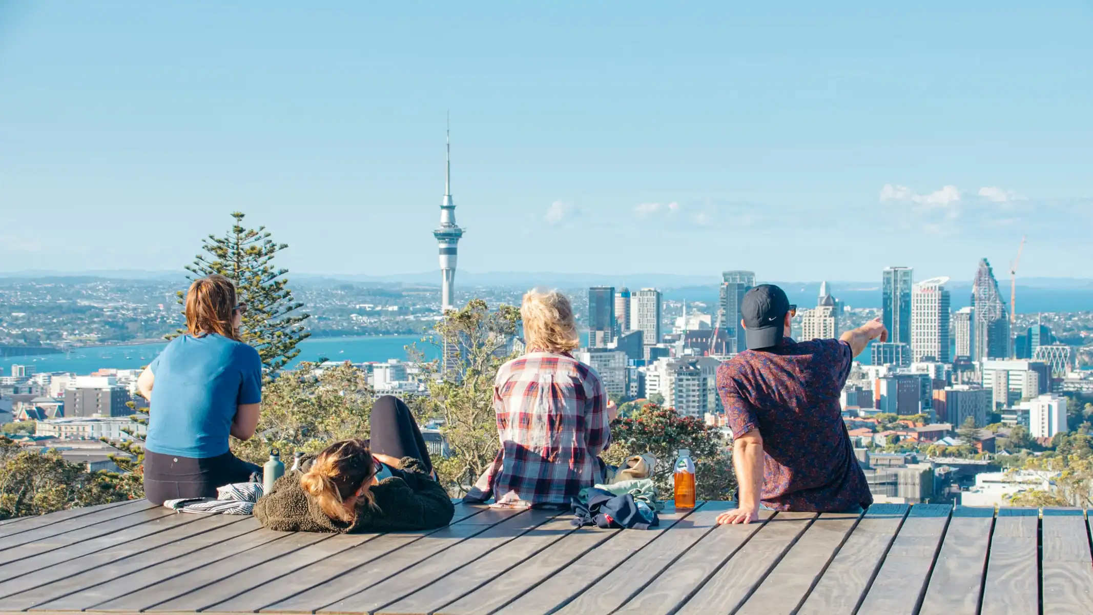Vibrant cityscape of Auckland, New Zealand, with people enjoying the view from a scenic lookout, highlighting travel and adventure opportunities.